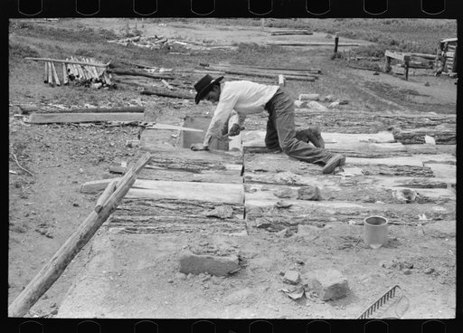 Spanish-American boy building a new roof for his home. Slabs of wood are used as a support for the mud that is later spread on. Amalia, New Mexico