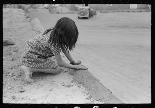 Spanish-American girl plastering edge of roof of adobe house. Costilla, New Mexico