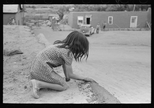 Untitled photo, possibly related to: Spanish-American girl plastering edge of roof of adobe house. Costilla, New Mexico