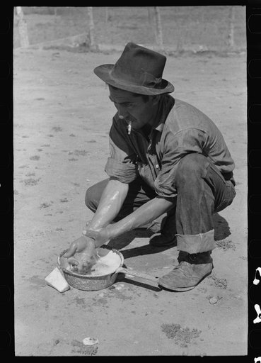 Spanish-American farmer washing his hands after dressing hog. Chamisal, New Mexico
