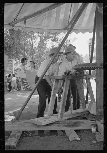 Power for the old-fashioned merry-go-round is furnished by two husky Spanish-American men, Taos, New Mexico