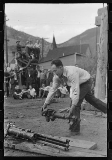 Untitled photo, possibly related to: Miner attaching airhose to power drill which he will use in drilling contest, Labor Day celebration, Silverton, Colorado