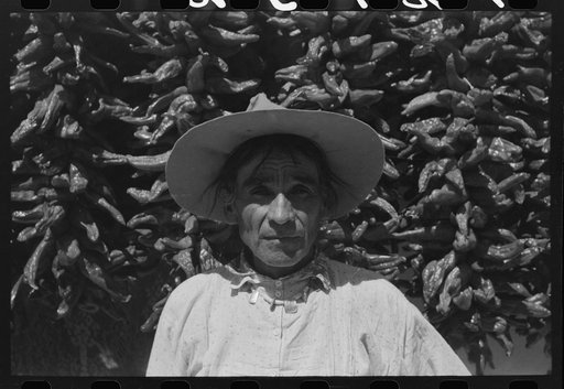 Untitled photo, possibly related to: Indian and his wife in front of house with chili peppers, Isletta, New Mexico