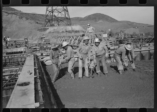 Construction workers using tools to settle freshly-poured concrete, Shasta Dam. Shasta County, California