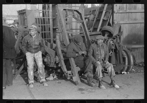 Men sitting on parts of truck in junkyard, South Side of Chicago, Illinois