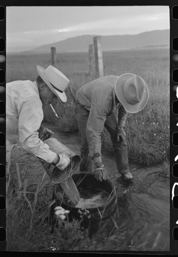 Untitled photo, possibly related to: Mr. Eddie Cruzen (with cigarette holder) and ranch hand mix up blue vitriol for treating hoof rot, Cruzen Ranch, Valley County, Idaho
