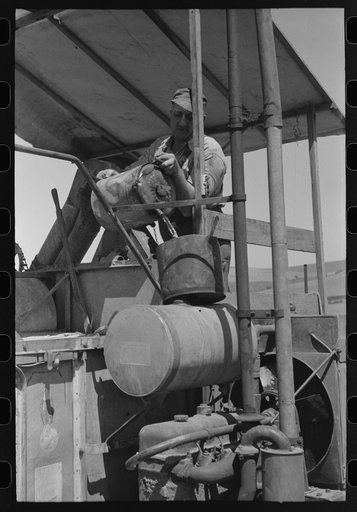 Pouring gasoline into combine engine. Walla Walla County, Washington