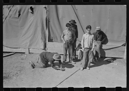 Agricultural workers play marbles. Yuma County, Arizona