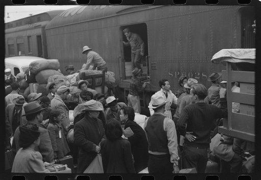 Los Angeles, California. The evacuation of the Japanese-Americans from West Coast areas under U.S. Army war emergency order. Japanese-Americans going to camp at Owens Valley gather around baggage car at the old Santa Fe Station