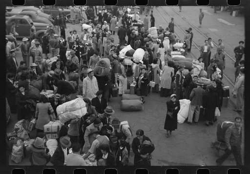 Untitled photo, possibly related to: Los Angeles, California. The evacuation of the Japanese-Americans from West Coast areas under U.S. Army war emergency order. Japanese-Americans going to camp at Owens Valley gather around baggage car at the old Santa Fe Station