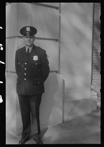 Washington, D.C. A policeman standing at the corner of a government building(?)
