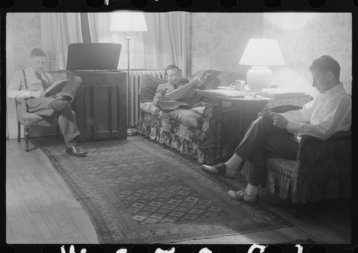 Washington, D.C. The room of a government clerk(?), showing three young men reading and listening to a radio in the evening