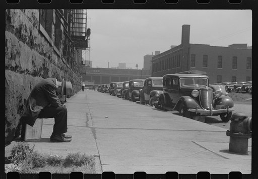 Man seated on corner of Jefferson Street and Vernon Park Place,] Chicago, Illinois
