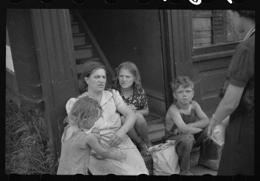 People sitting on steps in front of apartment. Superior, Wisconsin