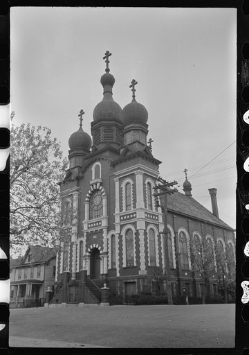 Possibly Mount Carmel, Pennsylvania] A brick church building with white stone trimming, towers, and a triple cross