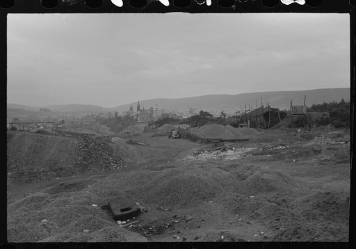 Mount Carmel, Pennsylvania] Church spires and houses as seen over many coalyards on the outskirts of the town which is silhouetted against a mountainous background
