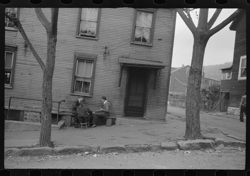 Shenandoah(?), Pennsylvania. Three men enjoying a game on a bench outside a porchless and yardless home on one of the sunken streets