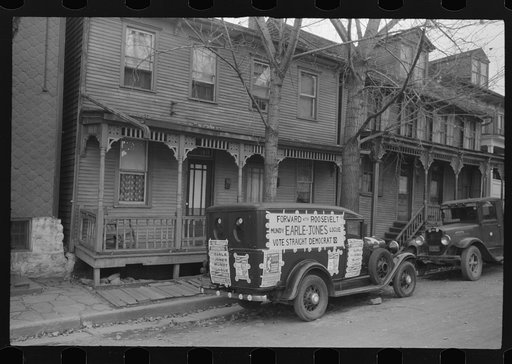 Shenandoah (?), Pennsylvania. Homes of a mining town, showing two trucks, one of which is labeled with political posters, standing in front of them.