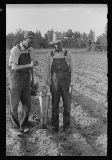 Untitled photo, possibly related to: Closeup of a tobacco planter in use. The hand in the upper left is holding a tobacco plant to be dropped into the planter. Near Chapel Hill, North Carolina