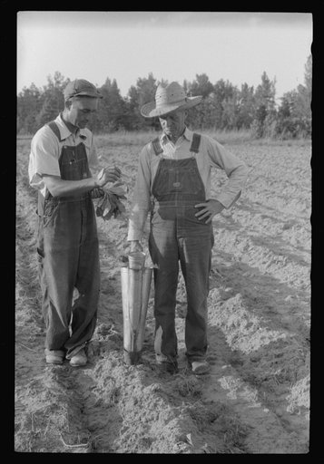 Untitled photo, possibly related to: Closeup of a tobacco planter in use. The hand in the upper left is holding a tobacco plant to be dropped into the planter. Near Chapel Hill, North Carolina