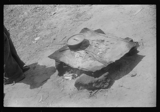 Untitled photo, possibly related to: Migratory worker getting a light from the improvised stove over which he had cooked his lunch. Camden, North Carolina