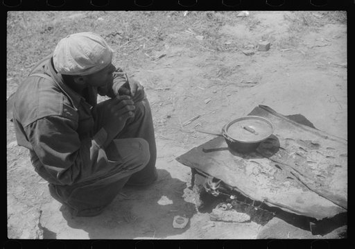 Untitled photo, possibly related to: Migratory worker getting a light from the improvised stove over which he had cooked his lunch. Camden, North Carolina