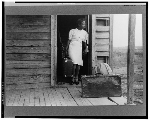 Florida migrant bringing her luggage out in preparation for a trip from Belcross, North Carolina to another job at Onley, Virginia