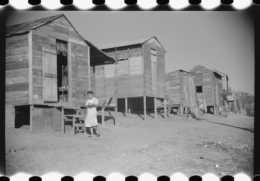 Street in slum area in Ponce, Puerto Rico. The land on which the houses stand rented from between eighty cents and a dollar a lot per month. Each person built his own house. They had to pay twenty cents per month for water