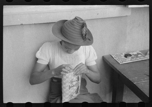 Untitled photo, possibly related to: French Village, a small settlement on St. Thomas Island, Virgin Islands. Young girl embroidering a straw basket to be sold in the handicrafts cooperative in Charlotte Amalie