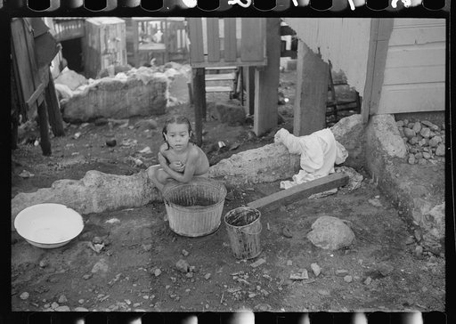 Little girl bathing on a street in a slum area in Yauco, Puerto Rico