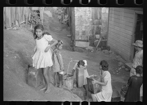 Children getting water from the faucet in the slum area in Yauco, Puerto Rico