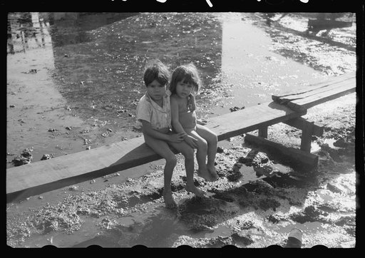 Children sitting on one of the boardwalks which are as sidewalks in the slum area known as "El Fangitto" (The Mud) in San Juan, Puerto Rico