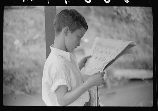Son of man living on houseboat on river reading paper. Charleston, West Virginia