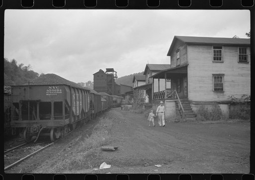 Untitled photo, possibly related to: Coal miner's child taking home kerosene for lamps. Company houses, coal tipple in background. Pursglove, Scotts Run, West Virginia
