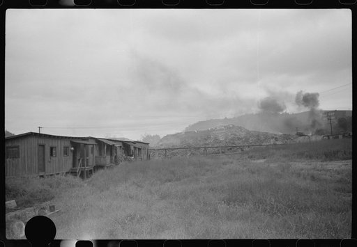 Untitled photo, possibly related to: Section of Rosedale Mining Company. Shanties by the river (burning slag pile to right). These used to be United Mine Workers barracks just thrown up to temporarily house men thrown out of company houses, during strike. Scotts Run, West Virginia