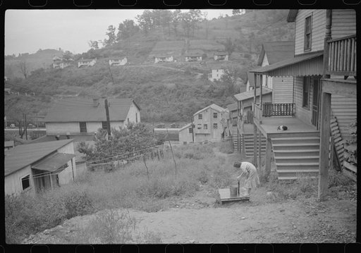 Coal miner's wife getting water from pump, company houses, Pursglove, Scotts Run, West Virginia