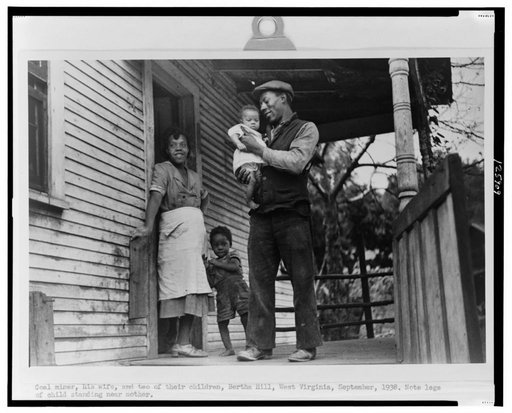 Coal miner, his wife and two of their children (note child's legs). Bertha Hill, West Virginia