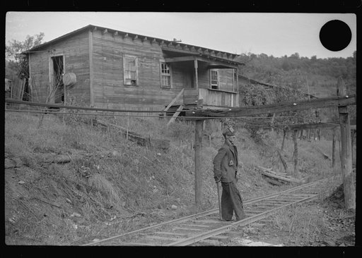 Untitled photo, possibly related to: Coal miner returning from work with pick over shoulder. The "Patch," Chaplin, West Virginia