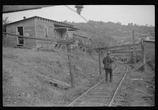 Untitled photo, possibly related to: Coal miner returning from work with pick over shoulder. The "Patch," Chaplin, West Virginia