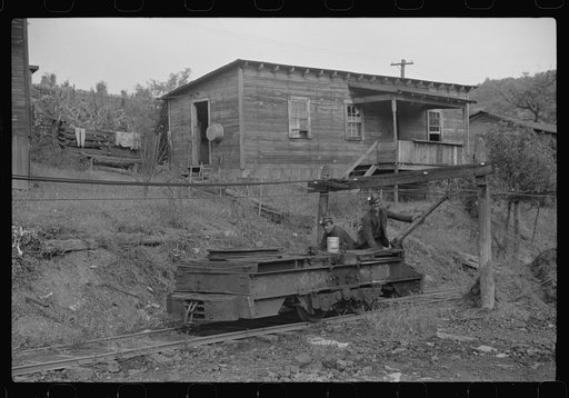 Untitled photo, possibly related to: Coal miner returning from work with pick over shoulder. The "Patch," Chaplin, West Virginia