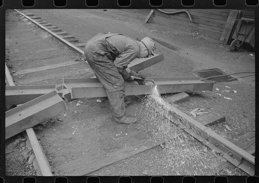Workman cutting a steel beam with an acetylane torch near mine tipple and engine house. Scotts Run, West Virginia