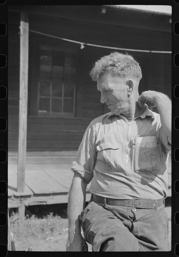 Untitled photo, possibly related to: Former coal miner sitting on his front porch. He is the town philosopher. He repairs his home (note railing and potato sack awning). Experiments with an elaborate garden on a hill about seven miles away. Jere, Scotts Run, West Virginia