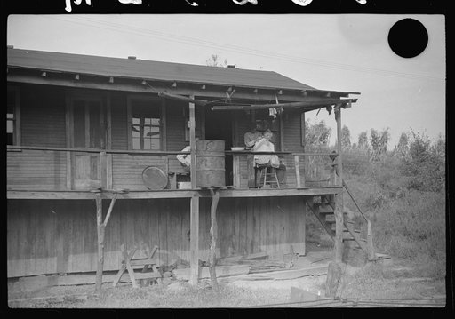 Untitled photo, possibly related to: Miners very often give each other haircuts on front porch. Note rain barrel. The "Patch," Chaplin, West Virginia