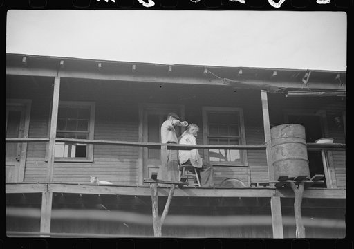 Miners very often give each other haircuts on front porch. Note rain barrel. The "Patch," Chaplin, West Virginia
