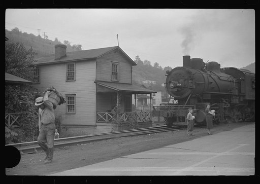 Untitled photo, possibly related to: Train pulls coal through center of town past miners' homes (company houses) several times morning and evening. Osage, West Virginia