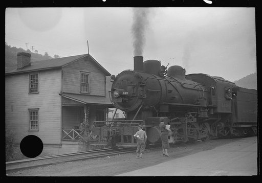 Untitled photo, possibly related to: Train pulls coal through center of town past miners' homes (company houses) several times morning and evening. Osage, West Virginia