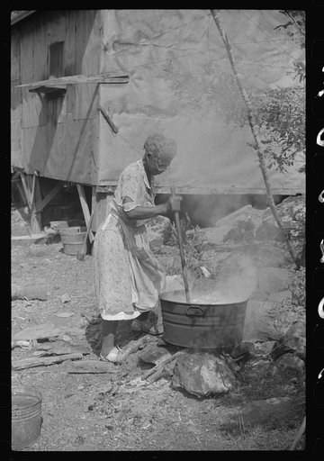 Negro woman washing clothes outside of shacks along the river, on the highway between Charleston and Gauley Bridge, West Virginia
