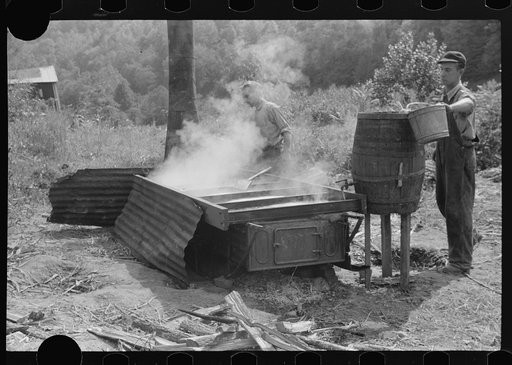 Untitled photo, possibly related to: Juice from sugarcane being poured into barrel. It is cooked in vat or still, into sorghum molasses. Racine, West Virginia