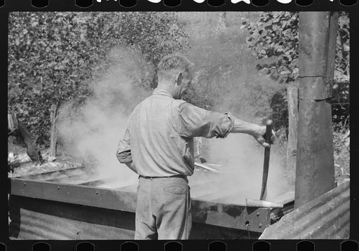 Farmer stirring sorghum molasses which is being cooked in vat. Racine, West Virginia