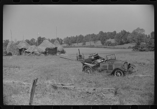 Old broken-down car and farm machinery in middle of farmer's field, West Virginia